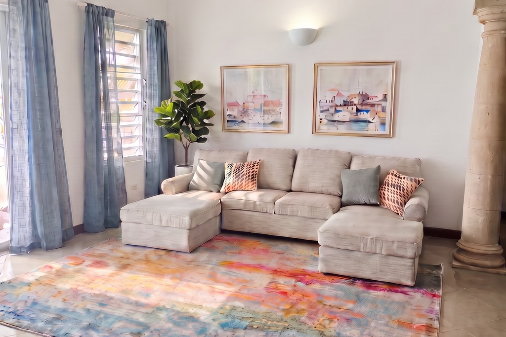 Second living room with light grey sectional, colorful abstract area rug and marina watercolors on the wall