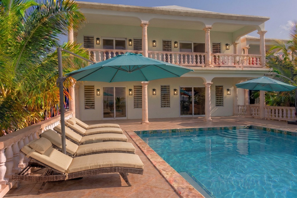 Villa Amaaj's Sea Salt façade and covered gallery behind the Aqua Blue infinity pool and turquoise cantilever umbrellas